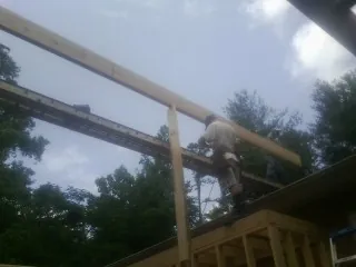 Carpenter setting a ridge beam over a new addition frame — Ice Dam Removal by Roofing Brothers in Aleppo