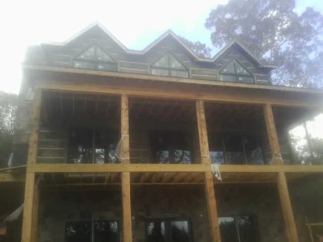 Dormers and porch framing on a large log home under construction — Roof Coating work by our crew in Aleppo