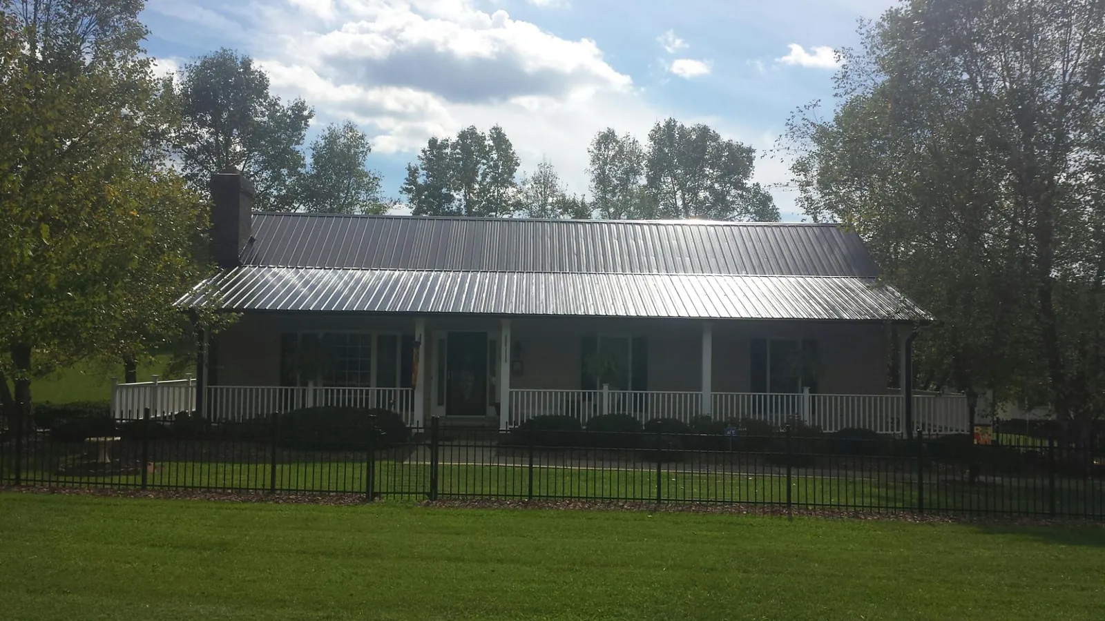 Gray metal roof on a brick ranch with a full width front porch — Gutter Guard Installation work by our crew in Aleppo