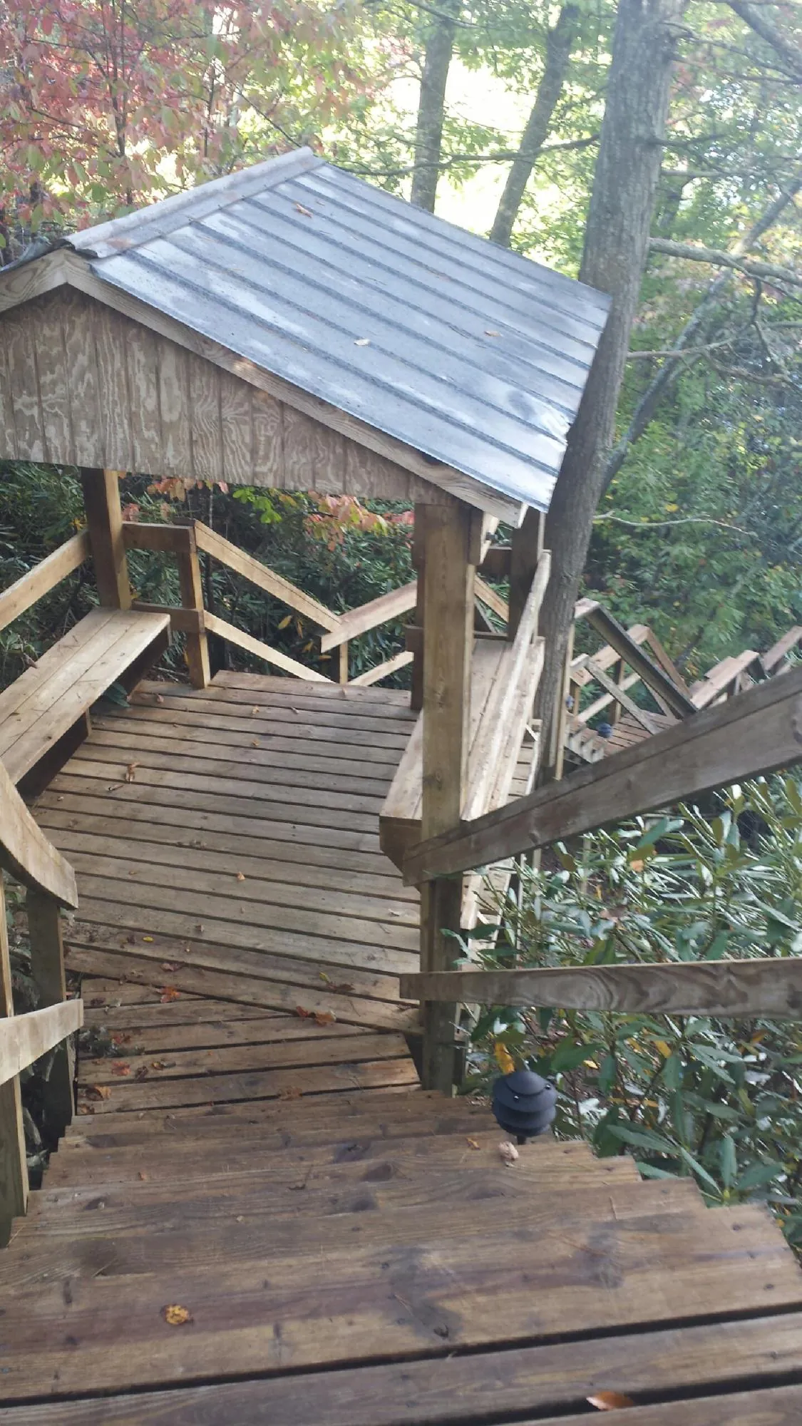 Metal roofed shelter over wooden steps on a wooded walkway — Skylight Repair & Installation work by our crew in Aleppo