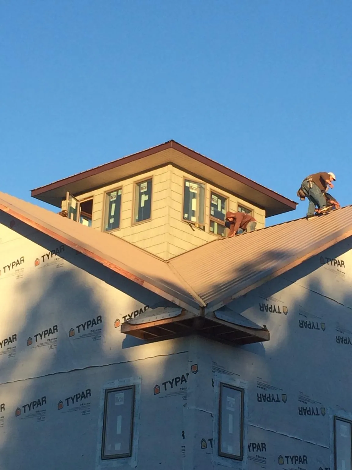 Roofers working around a rooftop cupola on a new metal roof at sunset — Roof Waterproofing in Aleppo by Roofing Brothers